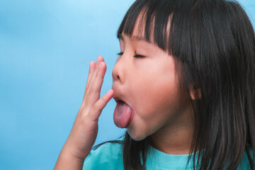 Little asian girl covering her mouth to smell the bad breath. Child girl checking breath with her...