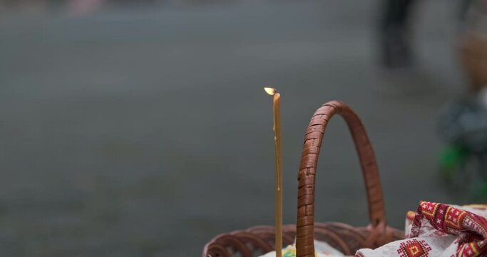 Burning and fading of candle standing in wicker basket. Religious holiday of Easter, the consecration of Easter eggs.
