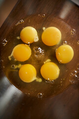 six raw eggs in a glass bowl on the table. Six 6 eggs in a glass bowl on a kitchen wooden table. Lots of fresh eggs in a bowl.