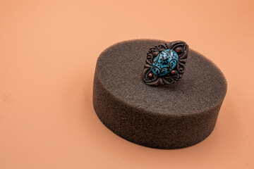 Metal ring with a blue gem on the soft platform with an isolated background. Close-up.