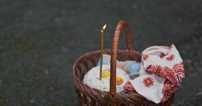 Man's hand lights candle standing in basket with Easter cake and towel. Celebration of Christian religious holiday of Easter.