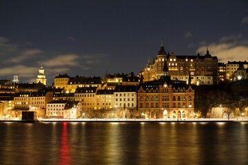 Fototapeta na wymiar Beautiful scenery of illuminated Stockholm waterfront view towards Sodermalm district with historic Mariahissen building and Monteliusvagen, Sweden 