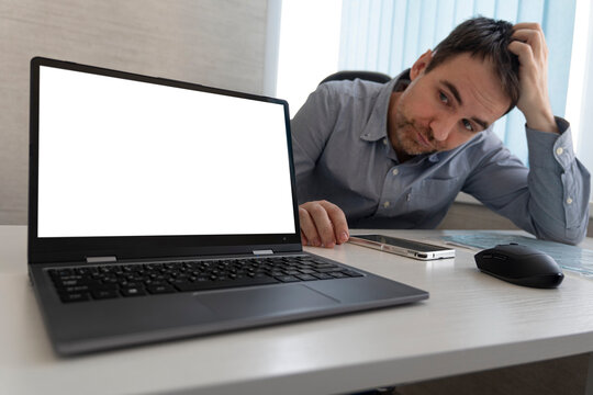 tired business man rubbing his head sitting at table in front of laptop in his office
