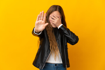 Child over isolated yellow background making stop gesture and covering face