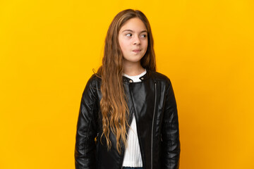 Obraz premium Child over isolated yellow background making doubts gesture looking side