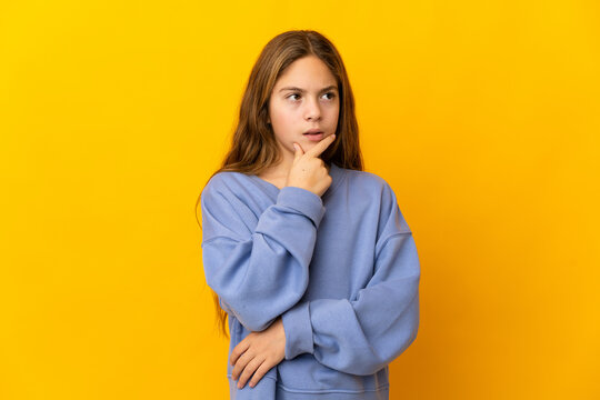 Child over isolated yellow background having doubts