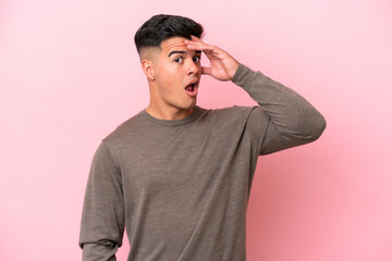 Young caucasian handsome man isolated on pink background doing surprise gesture while looking to the side