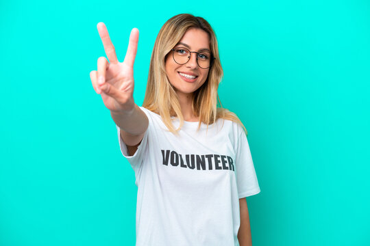 Young volunteer Uruguayan woman isolated on blue background smiling and showing victory sign