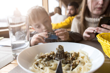 snail fillet pasta. delicacy in a restaurant. a woman with a child in the background.