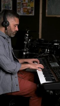 Musician man playing keyboard synthesizer piano in a recording studio. Music production.