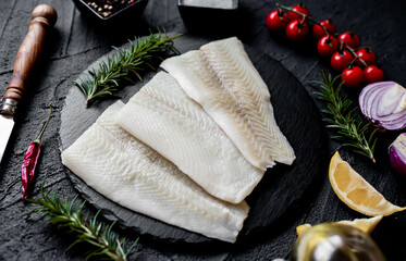 Fresh raw fillet of white fish Pangasius with spices on a stone background