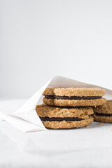 cookies packed in white parchment bags, chocolate filled oat cookies in a bakery bag, cookies in white paper bag