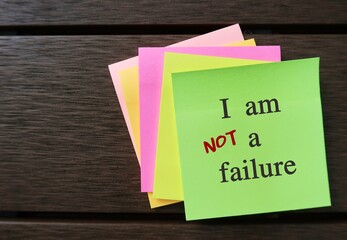Green note with message I AM A FAILURE, changed to I AM NOT A FAILURE - affirmation message or self...