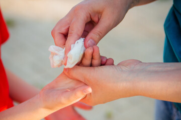 The woman's hands wipe the boy's child's hand with a napkin. Disinfection while walking.