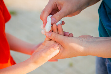 The woman's hands wipe the boy's child's hand with a napkin. Disinfection while walking.