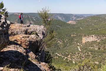 Una senderista sobre un poco admira el paisaje del parque natural del Alto Tajo en Guadalajara, Castilla La Mancha, España.
