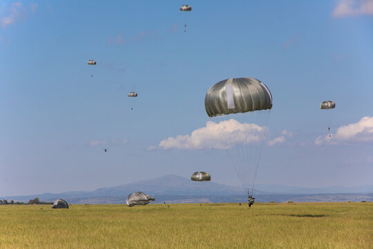 Un grupo de soldados paracaidistas toman tierra en el campo durante unas maniobras.