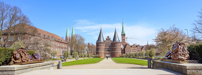 Wide panorama of the Lubeck Holstentor or Holsten gate park with two lion sculptures in front of...