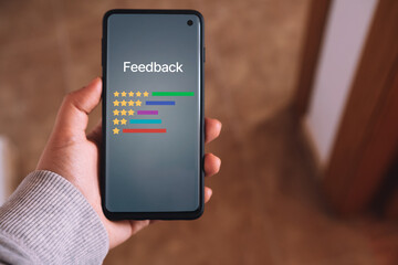 Woman hand holds a smartphone with consumer reviews interface on screen. Rating service. Online application for customers satisfaction. Feedback survey concept.