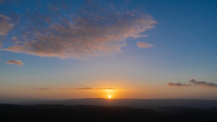 Vibrant red and orange hues of the setting sun stretch across the sky