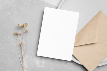 Blank wedding invitation card mockup with envelope and botanical decor, top view with copy space