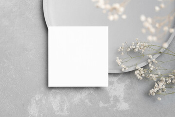 Blank square paper card mockup with gypsophila flowers decor, flat lay with copy space on grey
