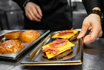 chef hand cooking cheeseburger on restaurant kitchen