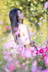 Beautiful woman happy traveler walking in the flowers garden. Young woman smile and relaxing with happy  around outdoor garden. Woman's hand touching and enjoying beauty cosmos flowers.Travel concept.