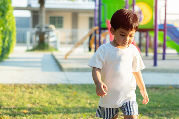 Portrait of cute cheerful baby Asian boy working or running on green grass in at playground.