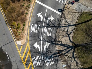 Top down drone view over yellow and white road markings for directions on an empty road