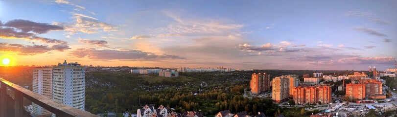 Beautiful sunset over the city filmed from a high floor of a house. Panorama of the city from above.
