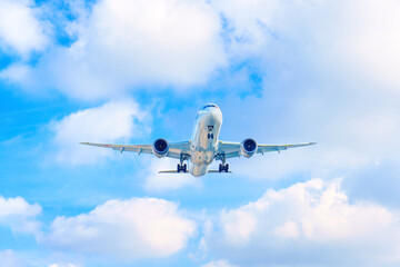 Passenger Plane Landing Against Blue Sky with White Clouds