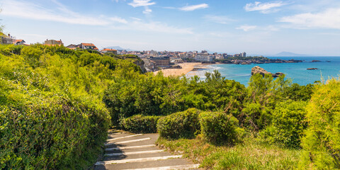Rocky steps and view of Biarritz seen from the Pointe Saint-Martin on a sunny day in France - obrazy, fototapety, plakaty