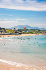 Tourists in the water and on the sandy beach of the Cote des Basques in Biarritz, France on a summer day