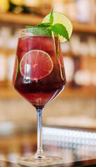 Cold pink cocktail with fresh grapefruit, lime and ice cubes on restaurant table
