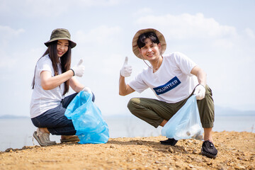 Group of Asian young people volunteer helping to collecting or picking up a plastic bottle garbage.
