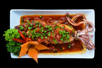 Fried squid in red sauce on black background for a menu