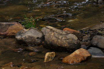 Naklejka na ściany i meble Large beautiful brown, yellow, gray stones and boulders in a mountain stream