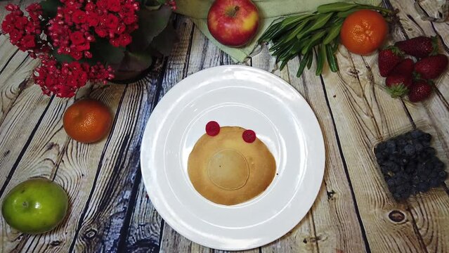 Cute pig pancake, mini pancakes assemble pig character on a white plate, wooden table with fruits. High quality 4k footage