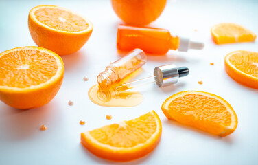 Vitamin C face skin care cosmetic concept - organic serum in a bottle and orange slices on white background.
