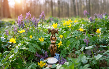 Triple Goddess Candlestick with candle on floral meadow, sunny natural background. Symbol of the...