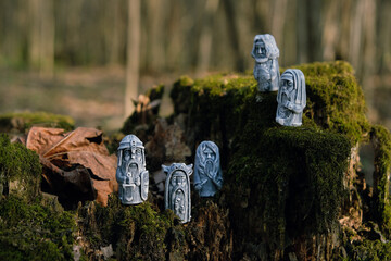 Antique ritual stone idols on tree stump close up, abstract natural forest background. gods totems...