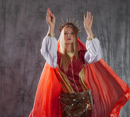 A beautiful young woman in a fantasy costume with a red veil and a golden crown
