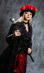 A pretentious Gothic lady in a long leather coat and a hat with roses, uses a cane.