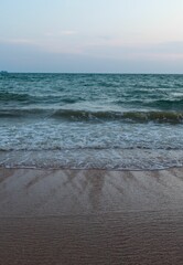 Scenic view of a beach on gloomy day, featuring tranquil blue ocean waves lapping against the shore