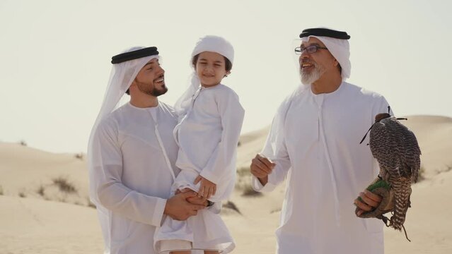Three generation family spending time in the desert with the falcon bird making a safari in Dubai. Concept about middle eastern cultures and lifestyle in the emirates