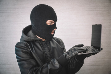 cybercrime, thoughtful hacking and technology crime - male hacker in room with laptop computer,...