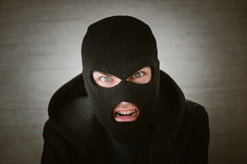 thief in a black jacket. A man in a black balaclava with an evil expression on his face. An...
