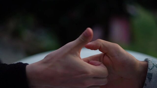 Closeup of two men playing thumb war on the blurred background