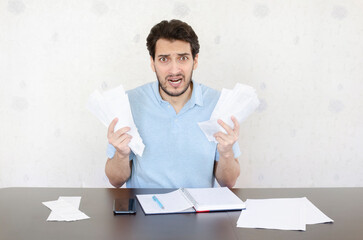 Close up of unhappy man sitting at the table, stressed and confused by calculate expense from...